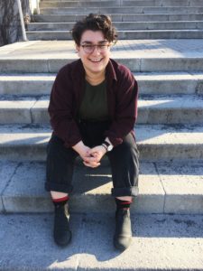 A young person sitting on concrete steps and smiling.